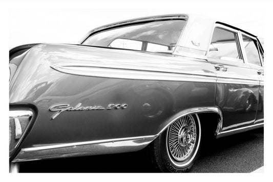 Black and white close-up photograph of a classic Chevrolet Galaxie 500 car, showing the rear quarter panel, chrome trim, wire-spoke wheel, and 'Galaxie 500' script emblem.